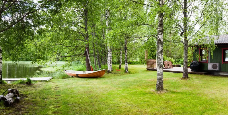Kesämökki järven rannalla ja ilmalämpöpumpun ulkoyksikkö mökin seinällä