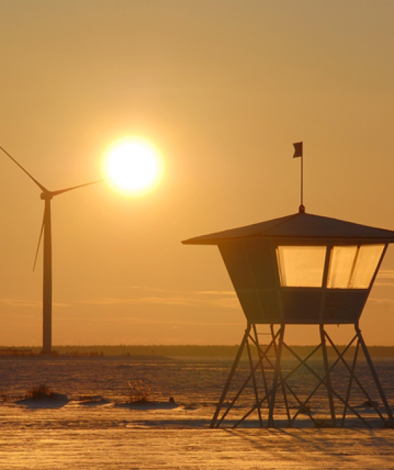 Kuva rannalta jossa näkyy taustalla tuulivoimaloita